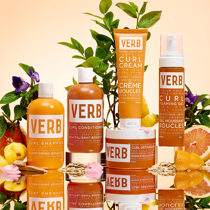 VERB curl care products including Curl Shampoo, Curl Conditioner, Curl Cream, Curl Defining Mask, and Curl Foaming Gel, each designed for all curl types to cleanse, detangle, define, moisturize, and reduce frizz. The image features bottles and a jar surrounded by natural elements like leaves, lemons, and grapefruit, with text in English and French.